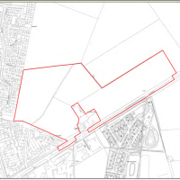 A land survey map showing a large plot of land outlined in red, located next to a residential area and a business park.