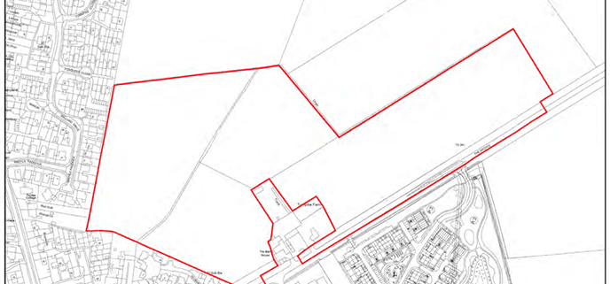 A land survey map showing a large plot of land outlined in red, located next to a residential area and a business park.